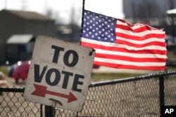 Tanda pemungutan suara dan bendera Amerika di luar lokasi pemilihan pendahuluan di Dearborn, Michigan, 27 Februari 2024. Michigan adalah negara bagian utama terakhir sebelum Super Tuesday dan negara bagian penentu dalam pemilihan umum November. (Paul Sancya/AP)