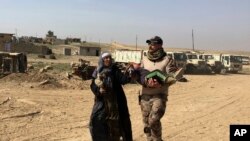 An Iraqi Army soldier helps displaced civilians as they flee their homes due to fighting between Iraqi security forces and Islamic State militants, on the western side of Mosul, Iraq, Tuesday, Feb. 28. 2017.