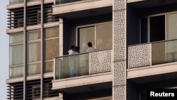 A policeman takes a photo on the balcony of a unit in which two women's bodies were found in a flat at Hong Kong's Wanchai district Nov. 1, 2014. 