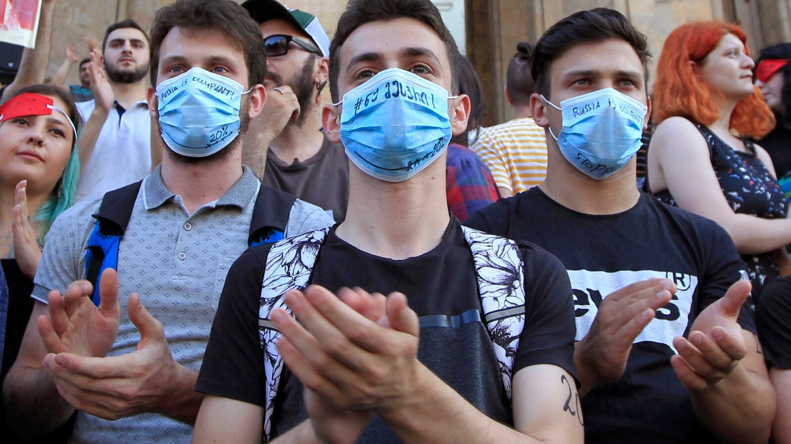 Young opposition demonstrators wearing masks reading "Russia Occupant " gather in front of the Georgian Parliament building in Tbilisi, Georgia, June 21, 2019.