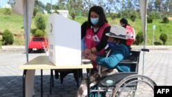 Una mujer indígena en silla de ruedas es asistida en un colegio electoral en Cuenca, Ecuador, el 11 de abril de 2021.