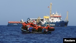 Sebuah kapal LSM Jerman memberikan pelampung kepada para migran di atas perahu kayu di lepas pantai Libya 1 Agustus 2021 lalu (foto: ilustrasi). 