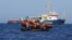 FILE — Crew members from the German NGO migrant rescue vessel Sea-Watch 3 give life jackets to migrants in international waters in the Mediterranean Sea, Aug. 1, 2021. Officials from Cyprus, Greece, Italy, Malta and Spain say more resources are needed to address migration.