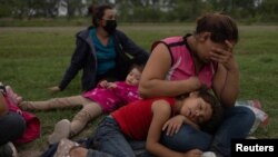 Migrantes de Honduras que busca asilo esperan para ser procesadas por agentes de la patrulla fronteriza de EE. UU. después de cruzar el río Grande hacia Estados Unidos desde México en La Joya, Texas, 19 de mayo de 2021.
