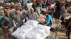 People load their carts with sacks of flour at a United Nations Relief and Works Agency aid distribution centre in Deir el-Balah in the central Gaza Strip on November 3, 2024, amid the ongoing war between Israel and Hamas.