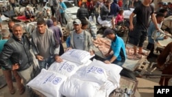 People load their carts with sacks of flour at a United Nations Relief and Works Agency aid distribution centre in Deir el-Balah in the central Gaza Strip on November 3, 2024, amid the ongoing war between Israel and Hamas.