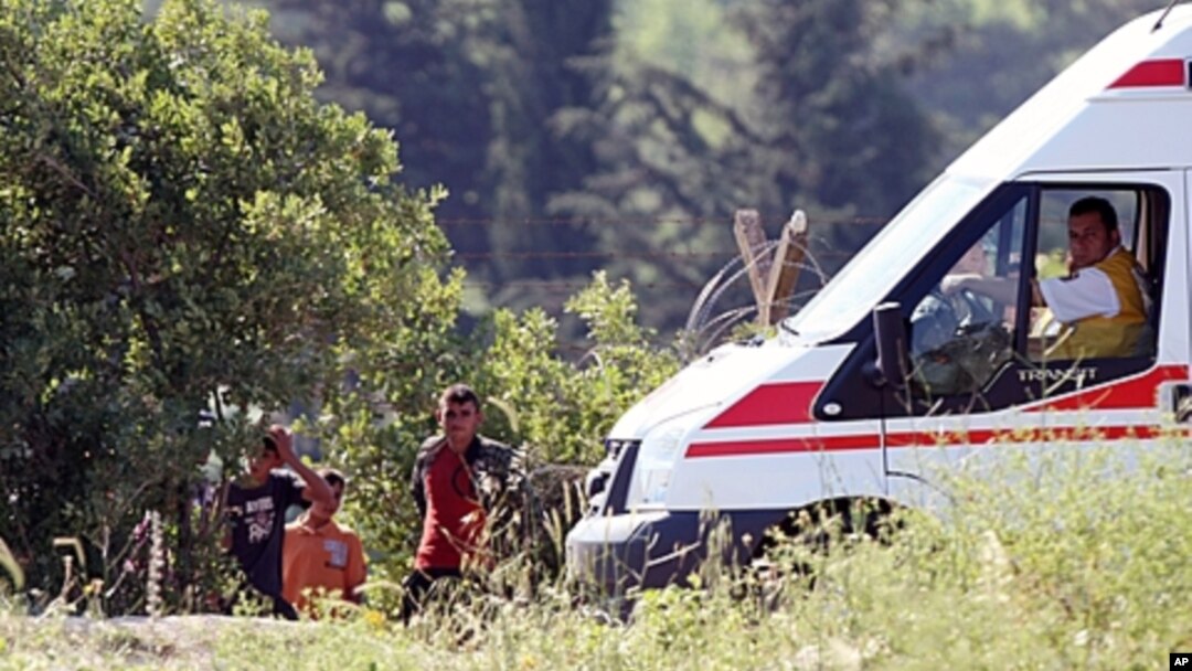 A group of Syrians wait next to a Turkish ambulance at the Syria-Turkey border inside Syria as they wait for the authorization to cross the border near the Turkish village of Guvecci in Hatay province, Turkey, June 9, 2011.