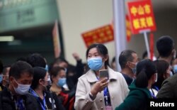 FILE - Migrant workers, wearing face masks to prevent the spread of coronavirus disease (COVID-19), arrive via a charter train from Jingzhou, Hubei province at Guangzhou South Railway Station in Guangzhou, Guangdong province, March 19, 2020.