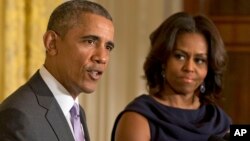 FILE - President Barack Obama, accompanied by first lady Michelle Obama, speaks in the East Room of the White House in Washington.