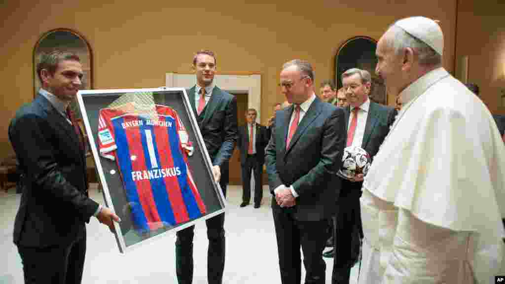 Sur cette photo fournie par le journal du Vatican L&#39;Osservatore Romano, le capitaine de l&#39;équipe Bayern, Philipp Lahm, à gauche, et le gardien Manuel Neuer présentent un maillot du Bayern au pape François lors d&#39;une audience privée avec l&#39;équipe et les responsables au Vatican, mercredi,