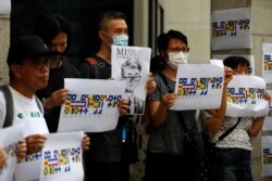 FILE - Demonstrators hold posters in support of Simon Cheng, a staff member at the consulate who went missing after visiting the neighboring mainland, during a protest outside the British Consulate-general office in Hong Kong, China, Aug. 21, 2019.