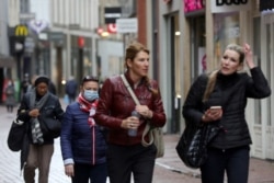 FILE - People with and without protective masks walk through the shopping street as the spread of COVID-19 continues in Amsterdam, Netherlands, Oct. 7, 2020.