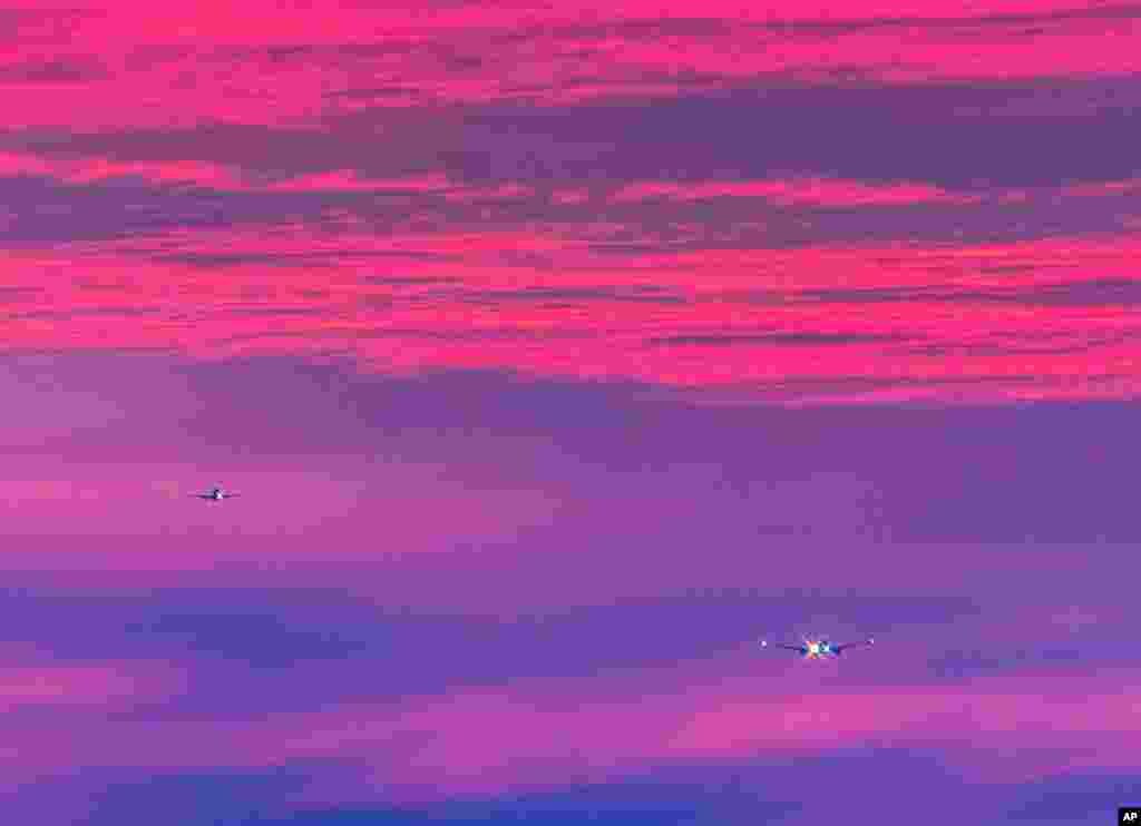 Two aircrafts approach the international airport in Frankfurt, Germany, as the sun rises.