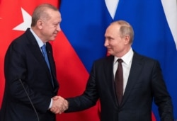 FILE - Turkish President Recep Tayyip Erdogan, left, and Russian President Vladimir Putin shake hands during a news conference following their talks in Moscow, Russia, March 5, 2020.