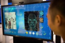 A man watches as a visitor tries out a facial recognition display at a booth for Chinese tech firm Ping'an Technology at the Global Mobile Internet Conference (GMIC) in Beijing, April 26, 2018.