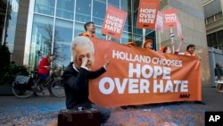 A man poses as crying firebrand anti-Islam lawmaker Geert Wilders during a small demonstration outside parliament, rear, in The Hague, Netherlands, March 16, 2017. 