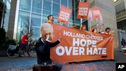 A man poses as crying firebrand anti-Islam lawmaker Geert Wilders during a small demonstration outside parliament, rear, in The Hague, Netherlands, March 16, 2017. 