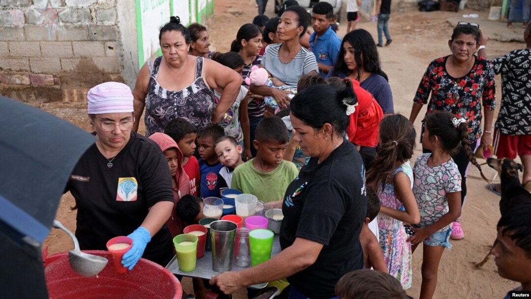 La gente recibe alimentos de Carolina Leal, directora y fundadora de la fundación Alimentando sueños, en Maracaibo, Venezuela, 12 de junio de 2024.