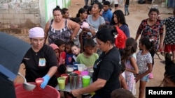 La gente recibe alimentos de Carolina Leal, directora y fundadora de la fundación Alimentando sueños, en Maracaibo, Venezuela, 12 de junio de 2024.