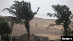 Seorang warga berjalan di pinggir pantai di Gopalpur di distrik Ganjam, Odisha, India (12/10).