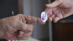 Một nhân viên phòng phiếu trao một miếng dán nhỏ có dòng chữ "Tôi đã bầu" cho một cử tri ở Stillwater, Oklahoma, hôm 1/3.