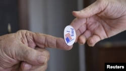 A poll worker hands a sticker to a voter on Super Tuesday in Stillwater, Okla., March 1, 2016.