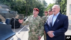 Belarus President Alexander Lukashenko, right, inspects police vehicles as he visits the Belarusian Interior Ministry special forces base in Minsk, Belarus, July 28, 2020.