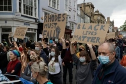 Supporters of the Rhodes Must Fall group, wearing protective masks against the spread of coronavirus, participate in a protest calling for the removal of a statue of Cecil Rhodes, a Victorian imperialist in southern Africa who made a fortune from…