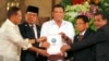 Philippine President Rodrigo Duterte, center, holds the draft of the Bangsamoro Basic Law (BBL) together with, government Peace Panel chief negotiator, Al-Hajj Murad, chair of Moro Islamic Liberation Front Monday, July 17, 2017 in Manila, Philippines.