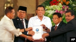 Philippine President Rodrigo Duterte, center, holds the draft of the Bangsamoro Basic Law (BBL) together with, from left, Secretary Jesus Dureza, government Peace Panel chief negotiator, Al-Hajj Murad, chair of Moro Islamic Liberation Front (MILF), Ghazal