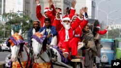 Para pria berpakaian Sinterklas untuk menyambut Natal di Lahore, Pakistan, Jumat (23/12). Pemerintah Pakistan juga meluncurkan kereta api khusus yang bertemakan Natal mulai Kamis (22/12) malam.