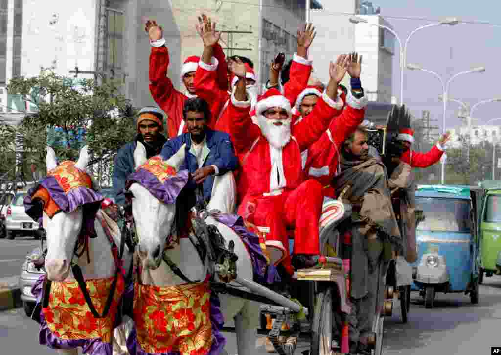 People dressed as Santa Claus ride a horse cart ahead of Christmas celebrations in Lahore, Pakistan, Dec. 23, 2013. 