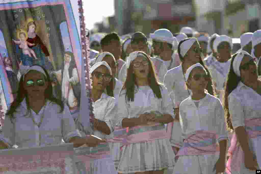 Girls sing as they carry an image of Our Lady of Rosary during the annual Afro-Christian Congada celebration in Catalao, Goias state, Brazil, Oct. 9, 2016. The group's leader sings a verse, and members repeat, making references to Brazil's history of slav