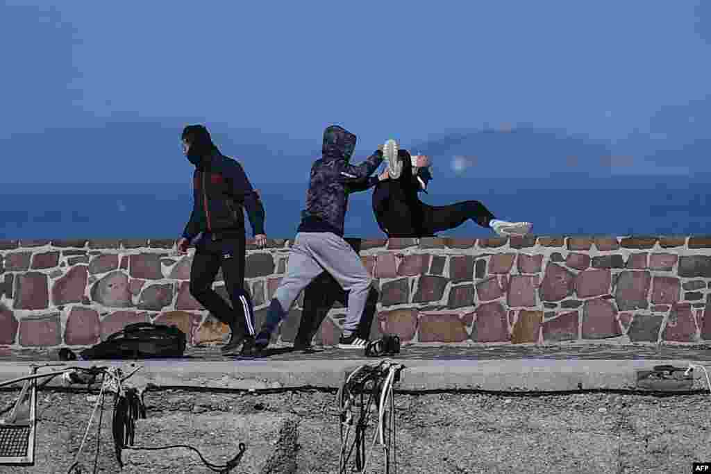 A journalist (R) is attacked by residents who are trying to prevent migrants from disembarking on the Greek island of Lesbos.