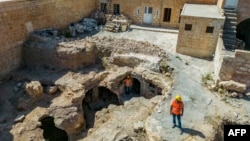 This aerial view shows municipal employees working outside the Matiate archaeological site underneath the town in Midyat in Mardin province, southeastern Turkey, on July 1, 2024.