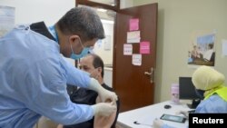 FILE - A Palestinian man receives the COVID-19 vaccine inside a medical center at Baqaa refugee camp, near Amman, Jordan April, 12, 2021.