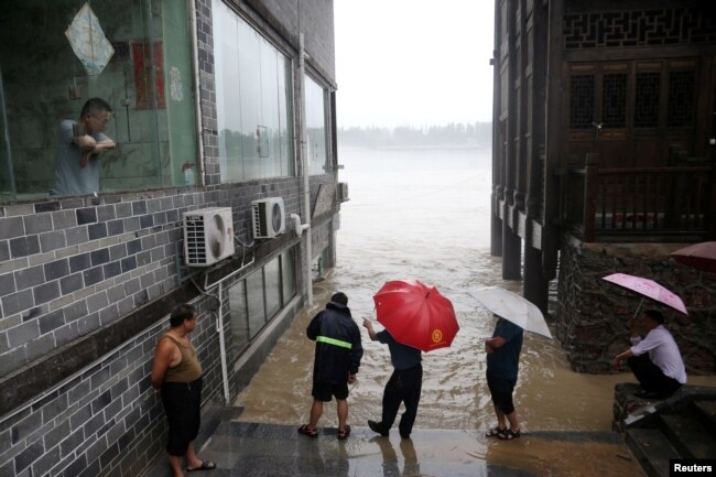 中国重庆市黔江区暴雨过后，人们观察到遭受洪水袭击的卓水古镇河流的水位上升。（2020年6月28日）