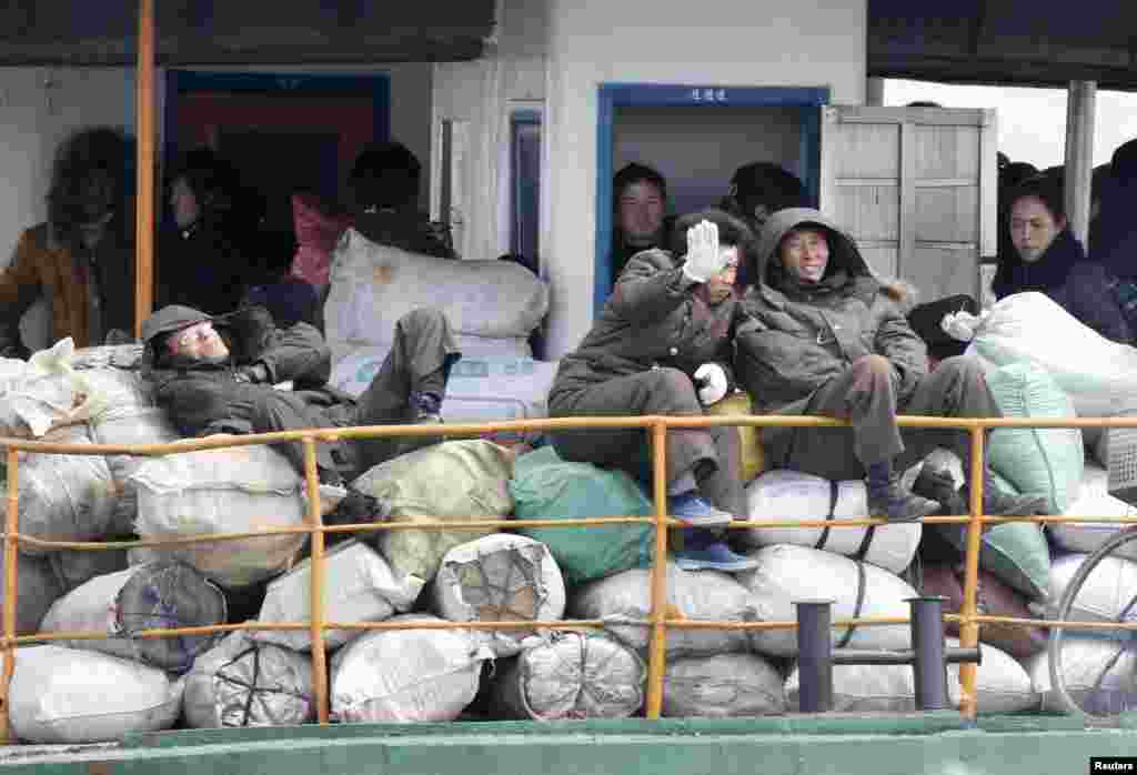 A North Korean man blocks his face with his hand from being photographed as he and other residents take a ferry in Yalu River, near the North Korean town of Sinuiju, opposite the Chinese border city of Dandong, April 11, 2013. 