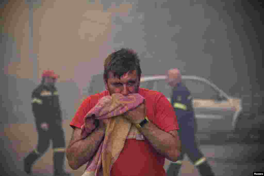 A man reacts to smoke as a wildfire burns at the village of Kontodespoti, on the island of Evia, Greece.