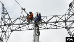 Deux agents de la société Eneo Cameroon effectuent des travaux, à Douala. (Crédit/Eneo)