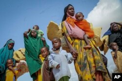 FILE - Somalis who fled drought-stricken areas carry their belongings as they arrive at a makeshift camp for the displaced on the outskirts of Mogadishu, Somalia, on June 30, 2022.