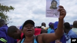 FILE—A woman holds a flyer with a portrait of Moreblessing Ali, at her burial on the outskirts of Harare, March, 2, 2024.