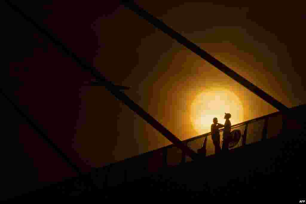Iraqi men stand along the Mohammed Baqir al-Sadr bridge at sunrise, during the Muslim fasting month of Ramadan, in Iraq&#39;s southern city of Basra, on April 23, 2021.