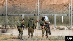 FILE - Israeli soldiers carry away an injured Palestinian who tried to approach the border fence east of Jabalia in the northern Gaza Strip, June 27, 2018.