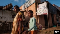 FILE - A woman and a girl walk in front of a sign inviting to vote in a referendum in order to create a new state in southern Ethiopia, in the town of Bonga, 100 kms southwest of the city of Jimma, Ethiopia, Aug. 17, 2021.