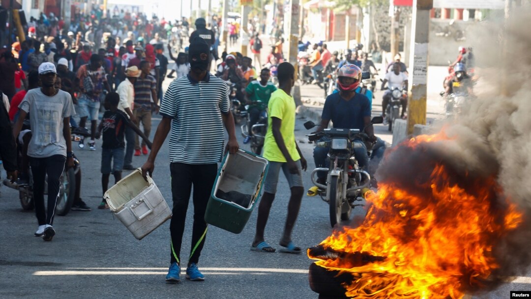 Manifestantes haitianos se congregan detrás de una barricada en llamas durante las protestas contra el presidente Jovenel Moise, en Puerto Príncipe, el 7 de febrero de 2021.
