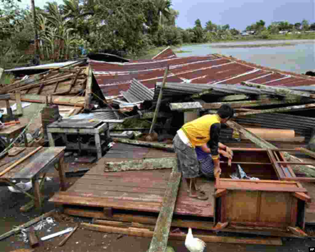 Residents prepare to assess their house which was damaged by Typhoon Bopha in Butuan city in southeastern Philippines Tuesday Dec. 4, 2012. A Philippine governor says at least 33 villagers and soldiers have drowned when torrents of water dumped by the pow