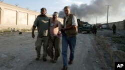 Afghan people assist an injured man after a bombing at the gate to a NATO compound in Kabul, Afghanistan, July 2, 2013.