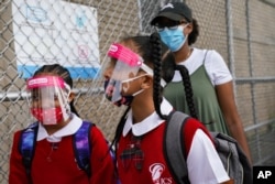 Students wear protective masks as they arrive for classes at the Immaculate Conception School while observing COVID-19 prevention protocols, Sept. 9, 2020, in The Bronx borough of New York.