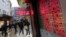 FILE - People walk by an electric board showing currency rates at a money exchange brokerage in Istanbul, Turkey, January 2014.